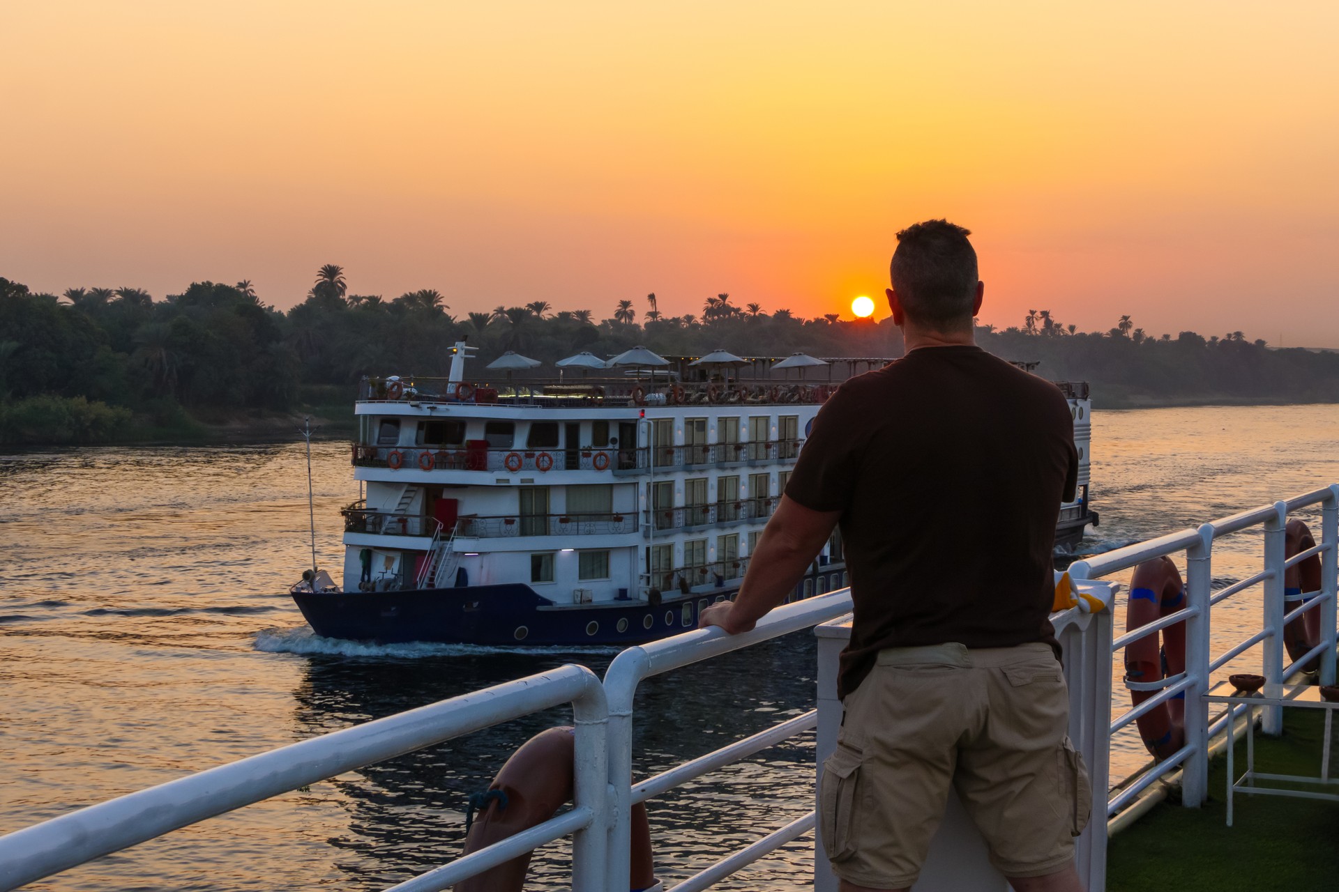 Man leaning over the railing at sunset in the Nile river